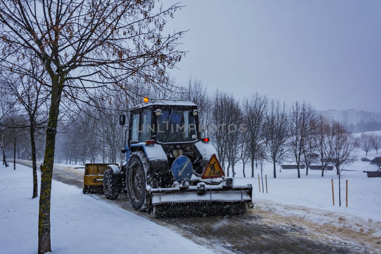 Traktor Balorus rensar snö från trottoaren under snöfall