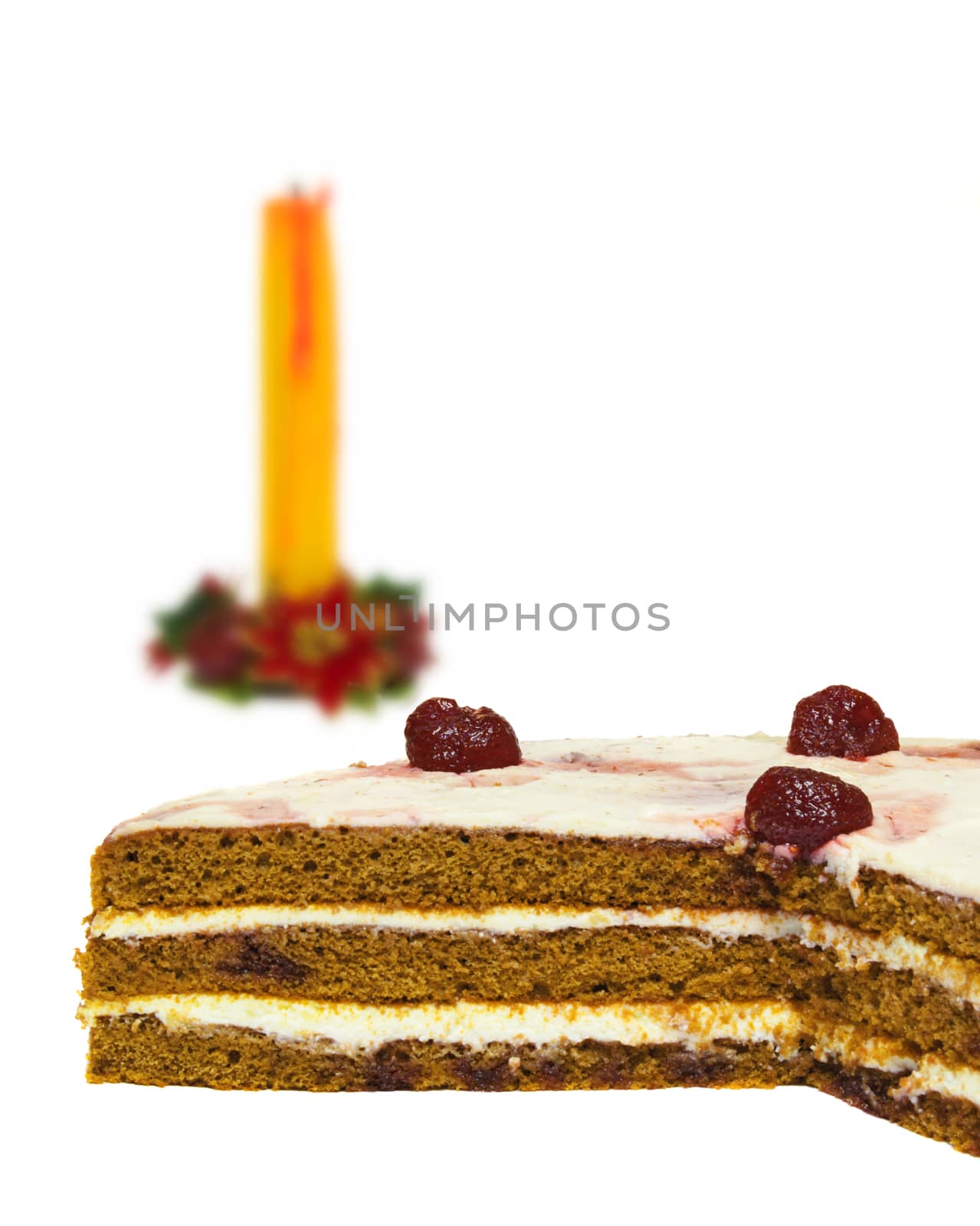 On a white background is clearly visible sponge layer cake. In the background, candle wax
