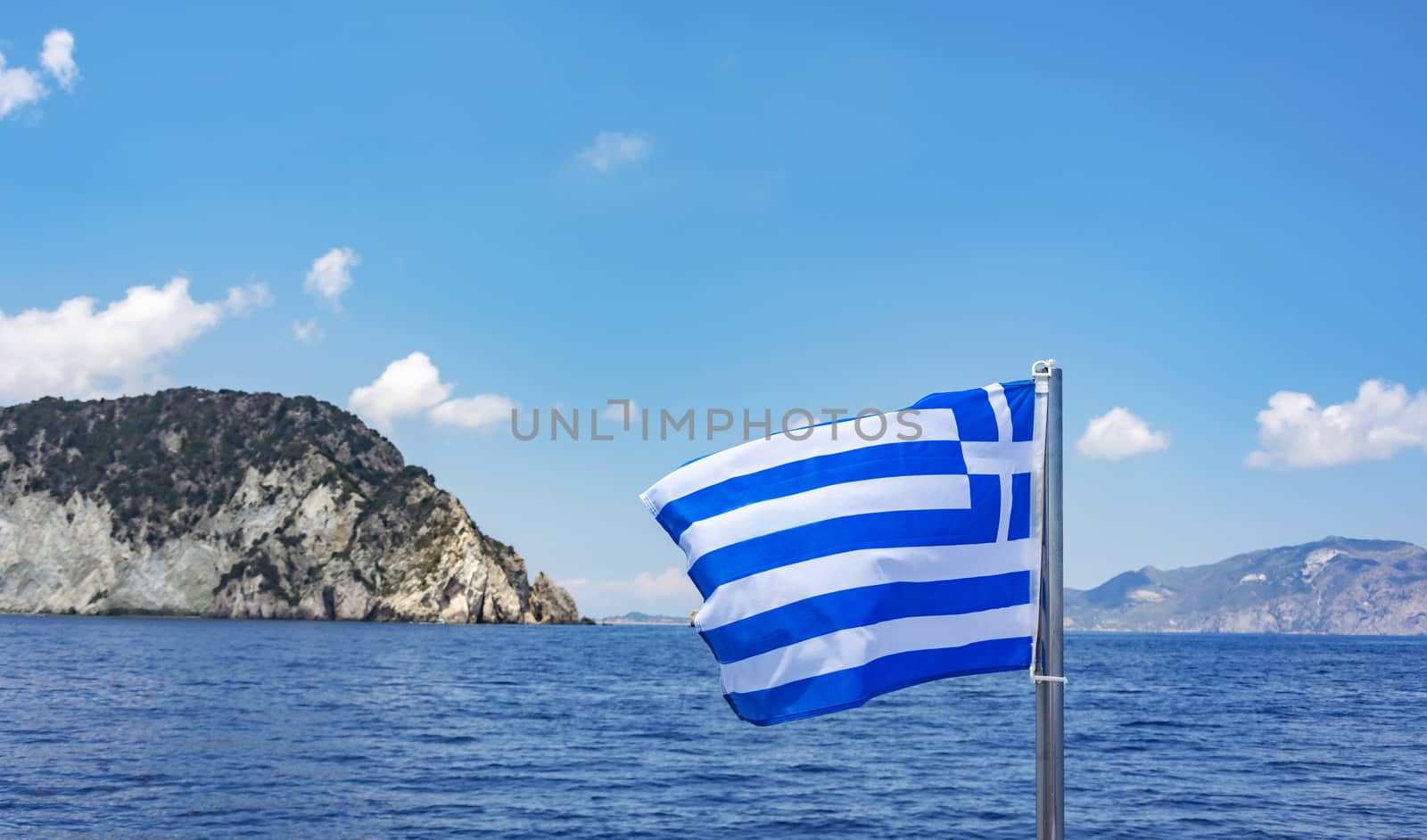 Against the backdrop of the sea and the mountains of Greece flag flies