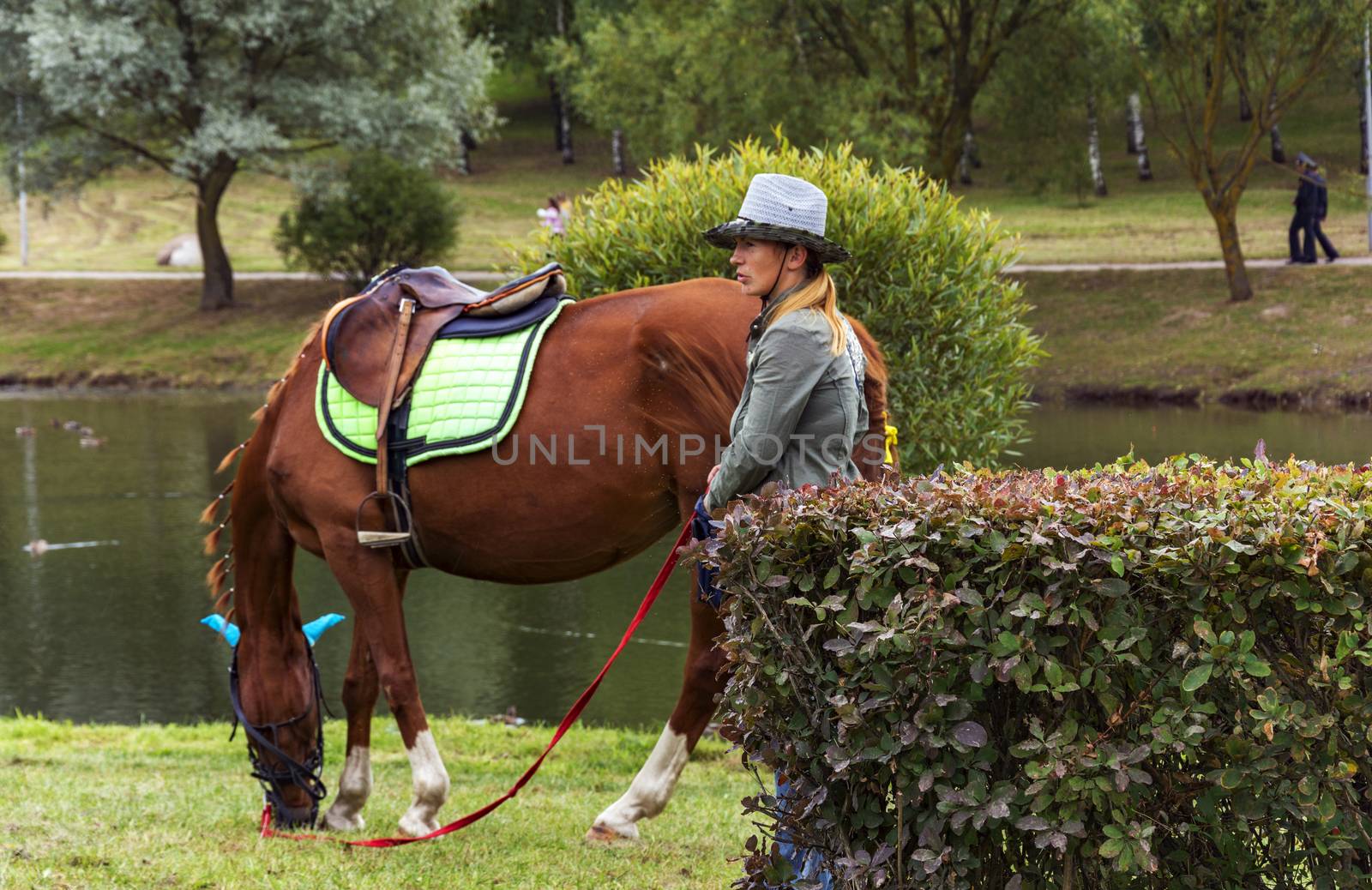 Girl in a cowboy hat and horse nibbling grass by Grommik