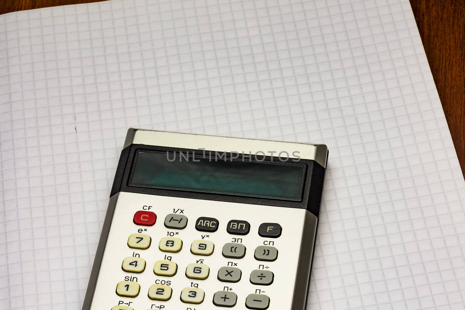 Calculator lying on a sheet of paper into the cell from a notebook for records