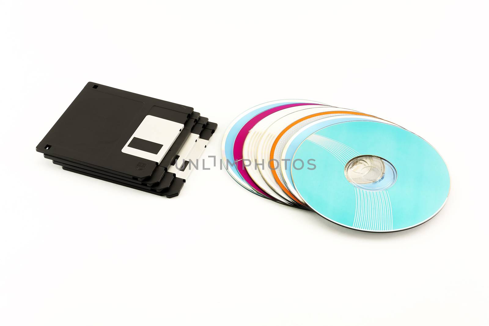 1.44 inch Floppy disks and CD / DVD discs lie on a white backgro by Grommik