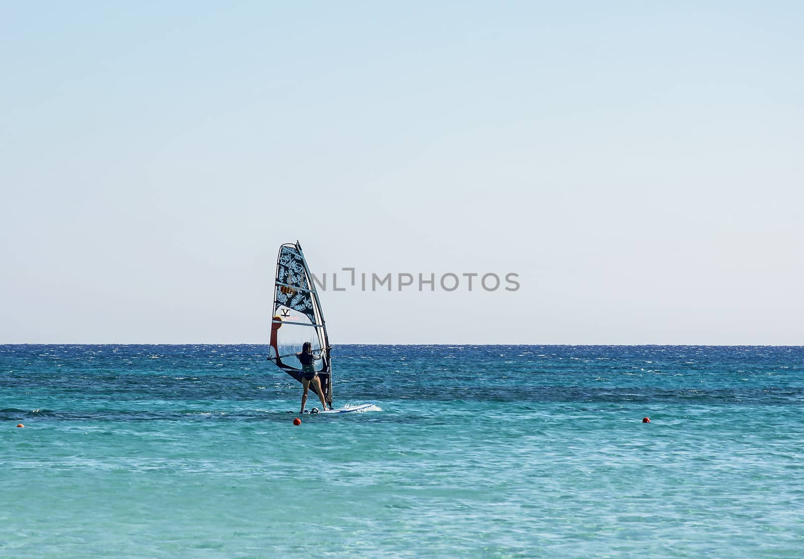 Windsurfing on the board with a sail on the sea waves by Grommik