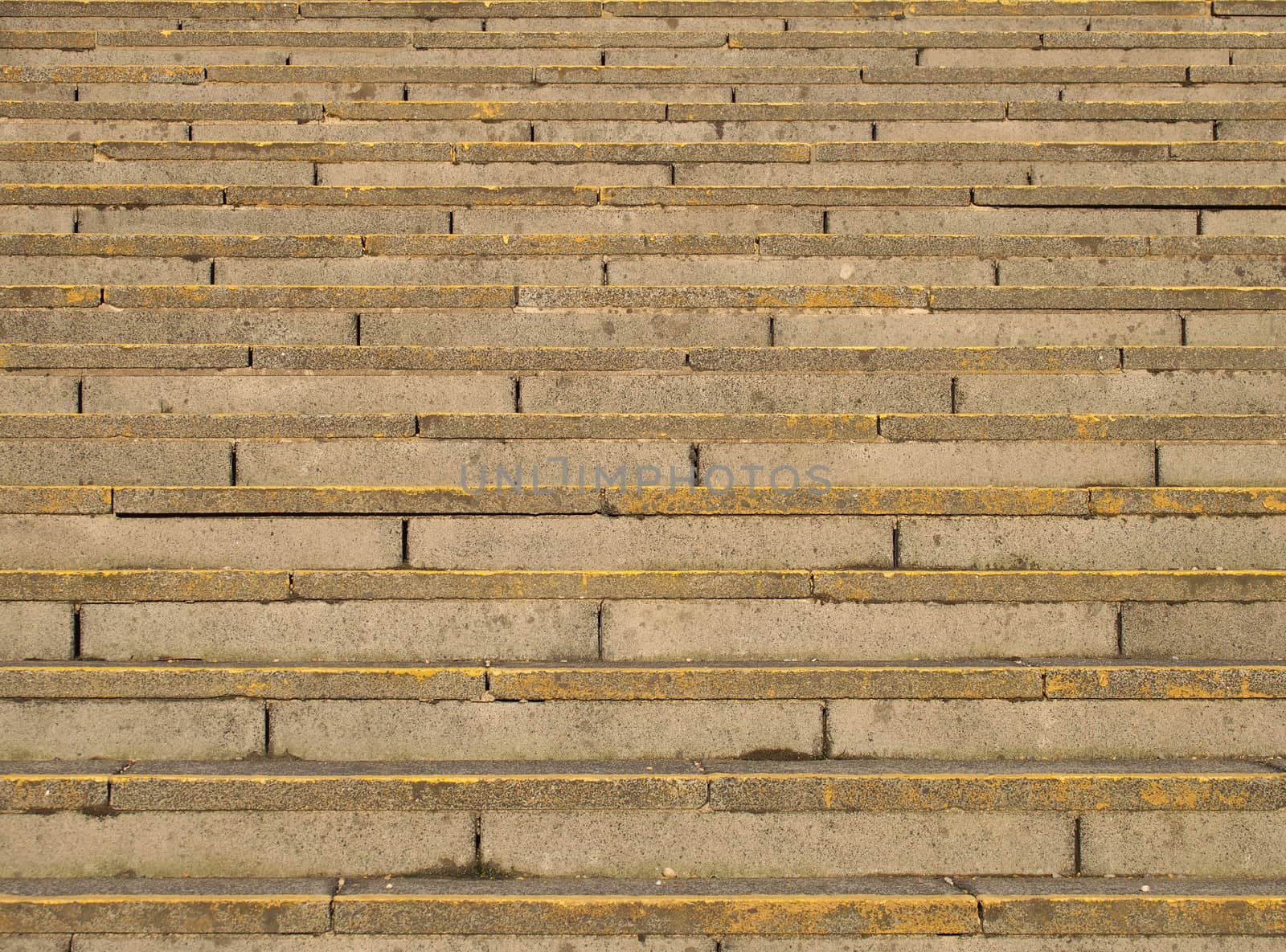 full frame image of old rough concrete stairs with rows of steps in perspective and traces of yellow paint