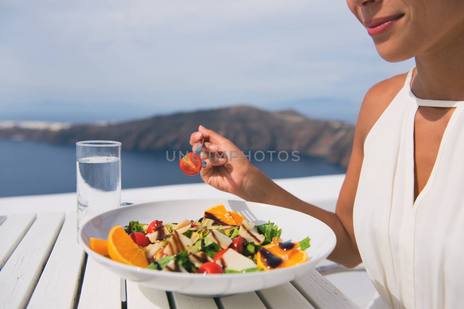 Restaurant woman eating salad luxury europe travel Santorini vacation. Healthy lifestyle people relaxing on Greece holidays by Maridav