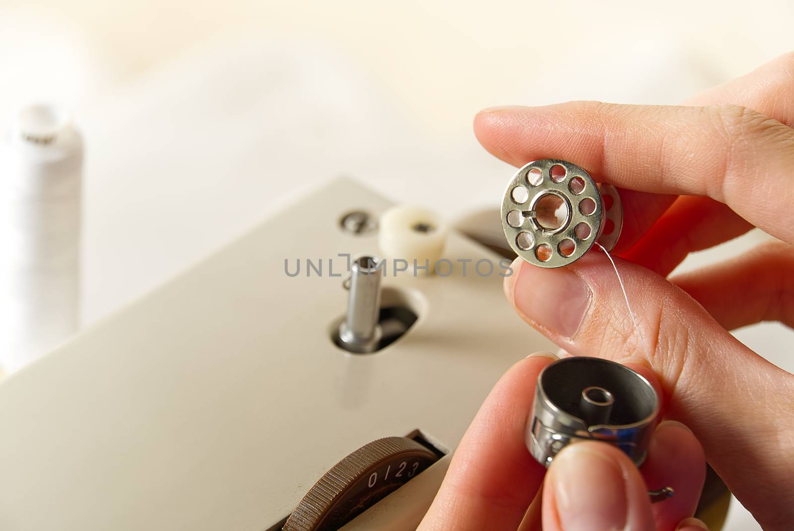 hands of a seamstress winding thread from a spool to a bobbin, close-up. by PhotoTime