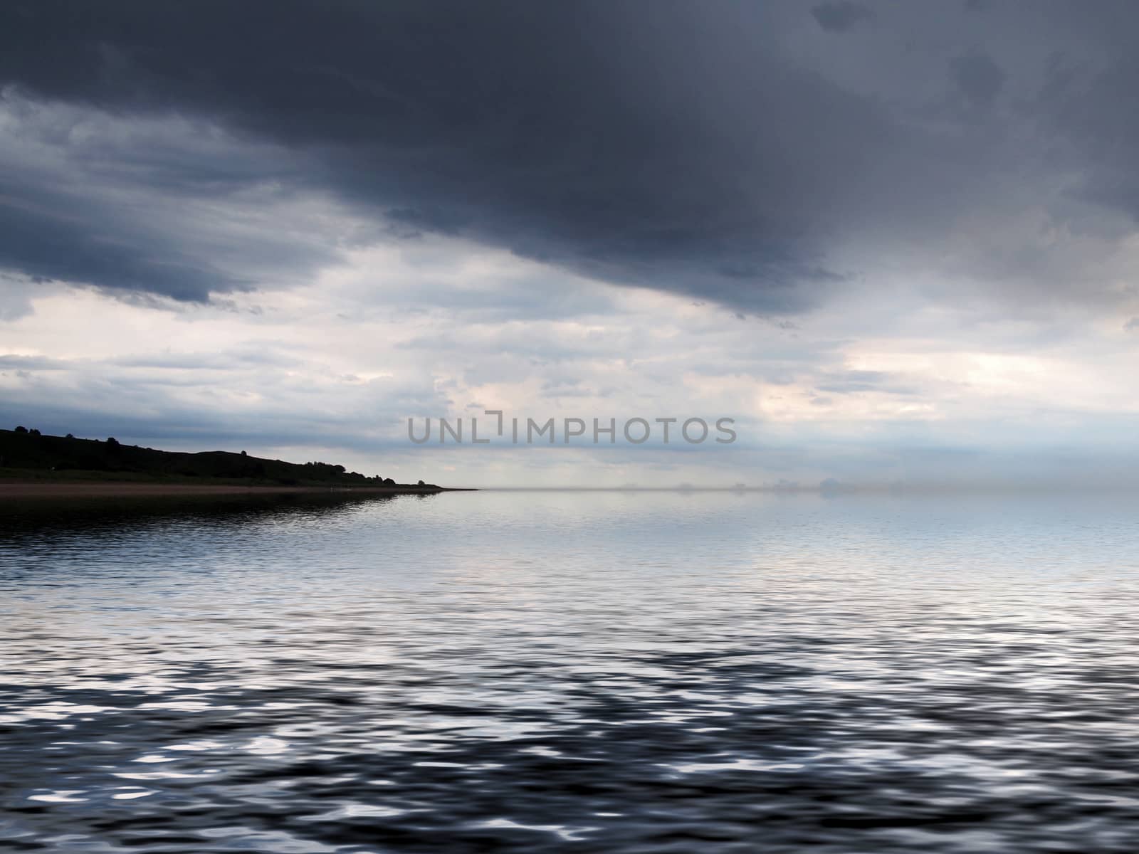 a distant coast reflected in the sea with dramatic dark storm clouds