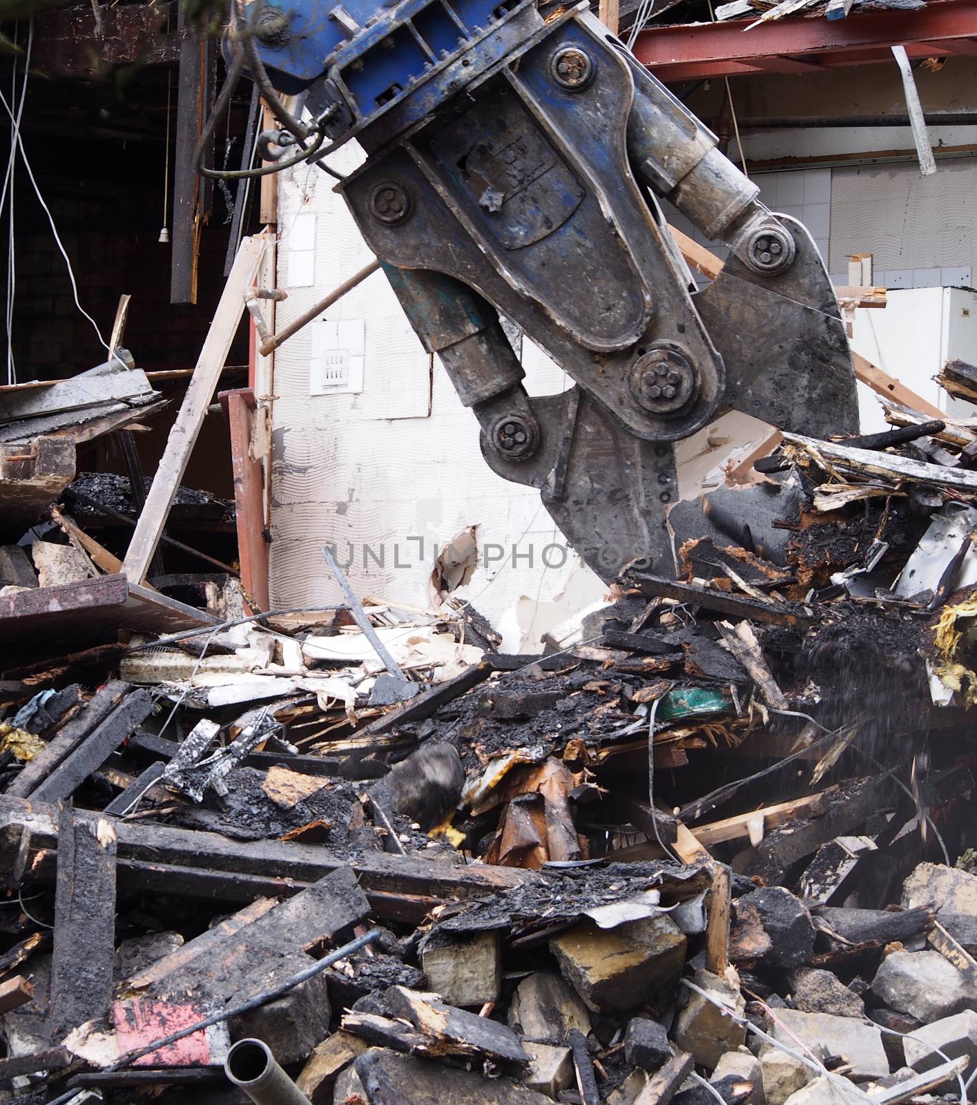 close up of a demolition claw working picking up debris in the wreckage of a destroyed building