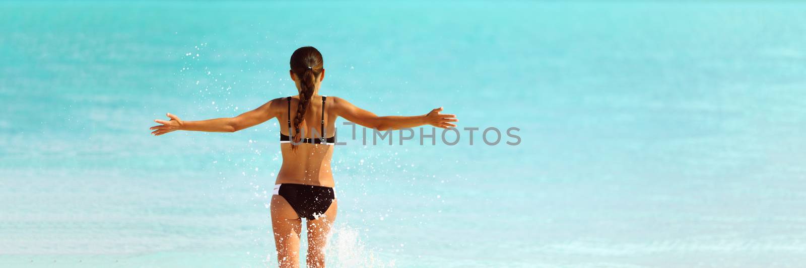 Happy bikini beach vacation woman running to ocean splashing water with open arms in freedom. Happiness carefree lifestyle banner with blue copyspace.