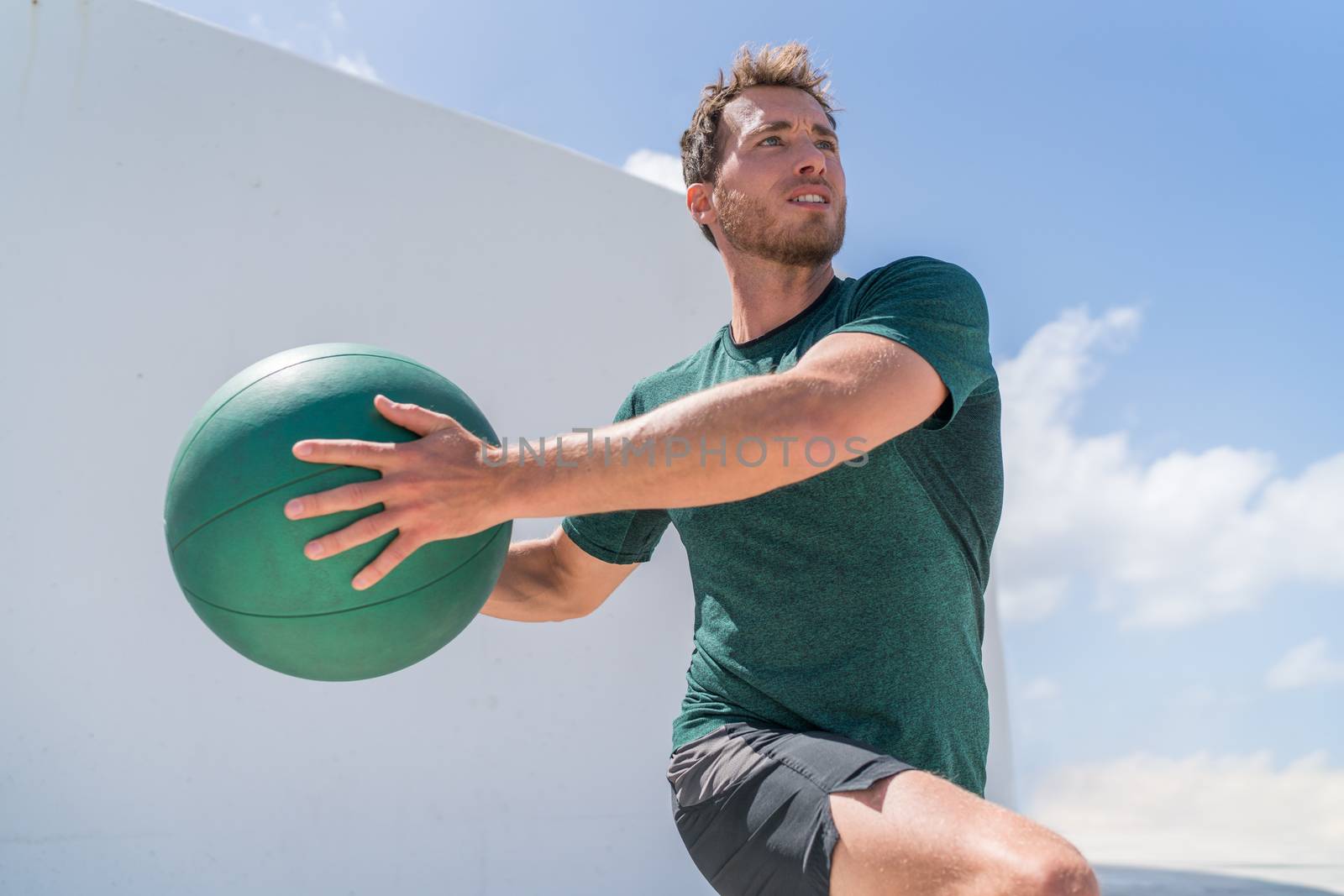 Fitness man training at gym working out legs and abs doing lunges twisting the torso for core workout with medicine ball weight. Crossfit body workout.