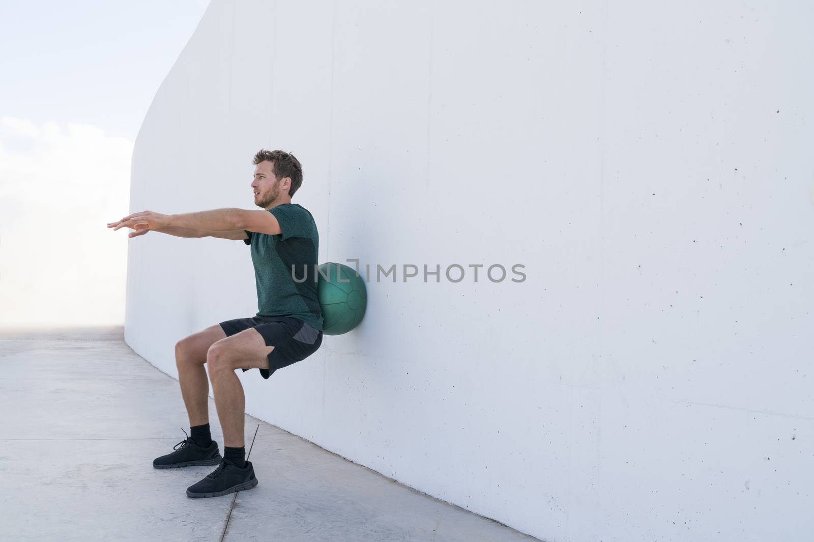 Strength training man doing medicine ball squats by Maridav
