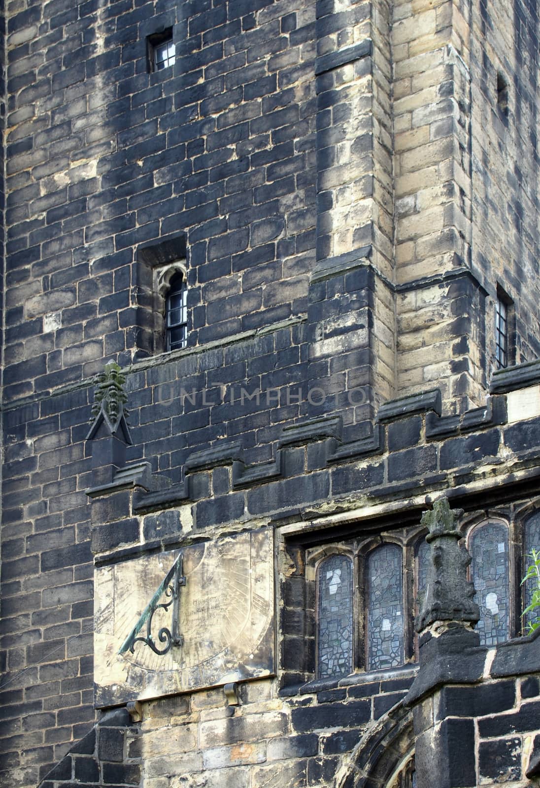 a full frame close up of ancient stonework stained glass windows and a sundial on the medieval church of st john the baptist in halifax now a minster