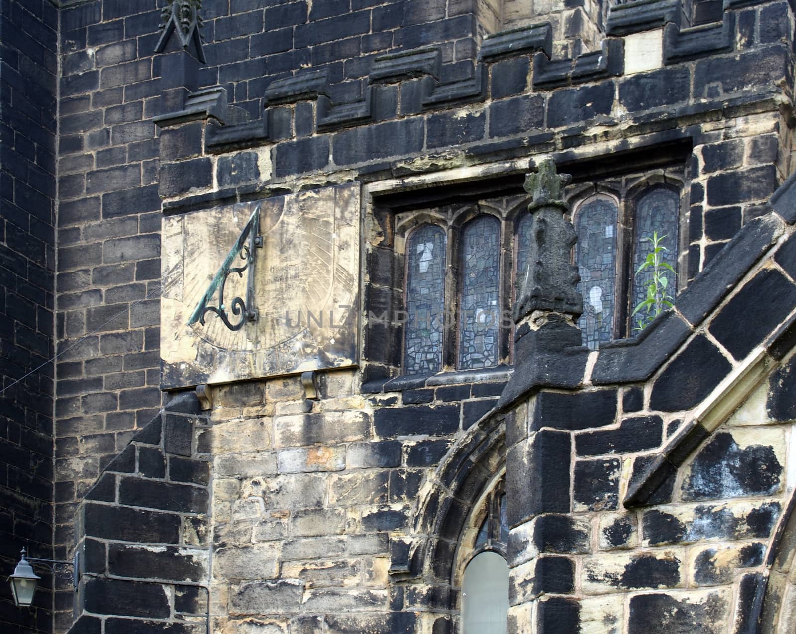 a full frame close up of ancient stonework stained glass windows and a sundial on the medieval church of st john the baptist in halifax now a minster