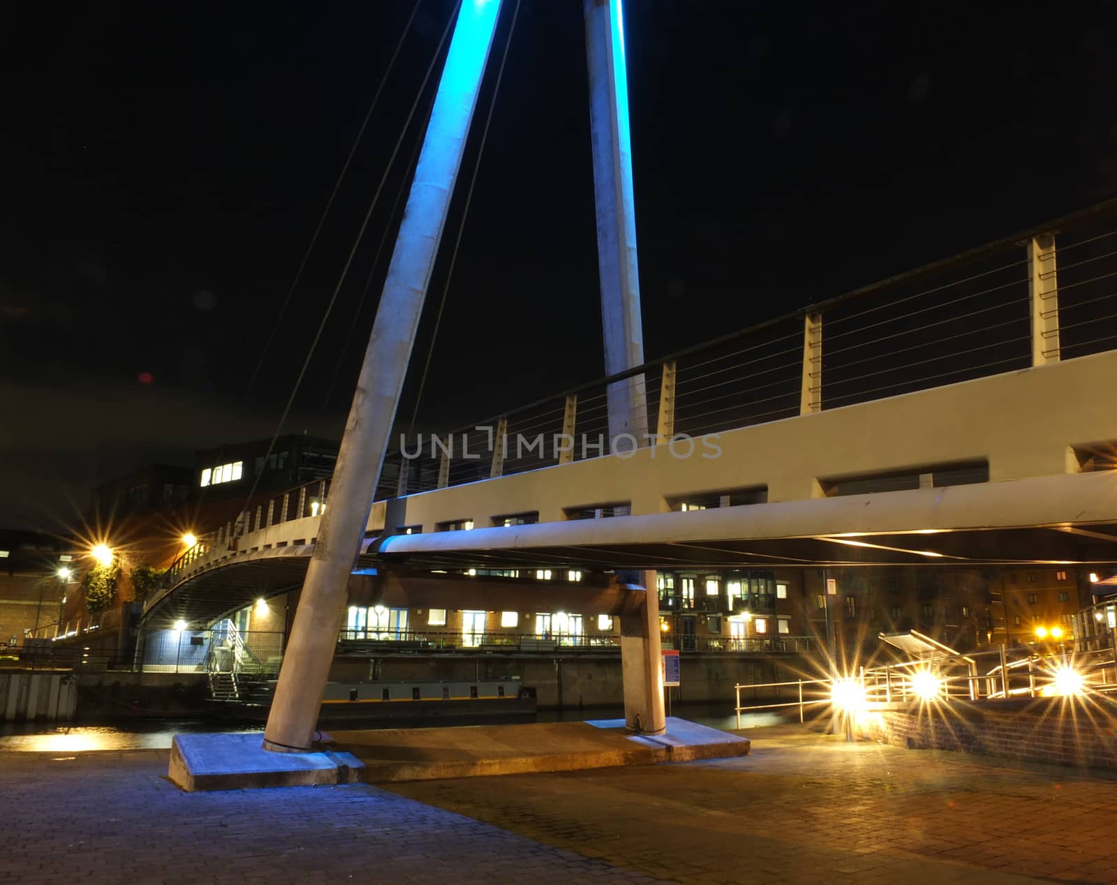 detail of the pedestrian footbridge crossing the river aire in leeds at night with bright lights and illuminated waterside buildings