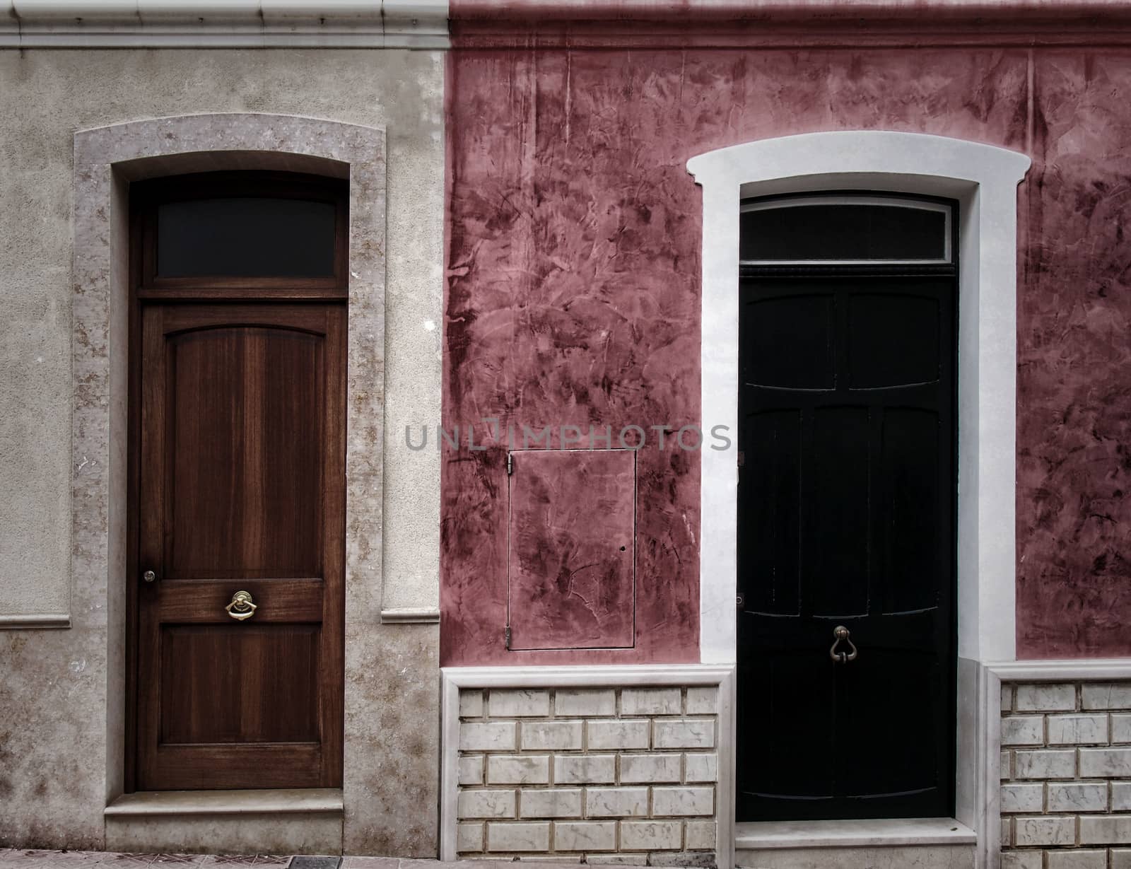 two neighboring different colored front doors next to each other in residential old houses painted in pink and white