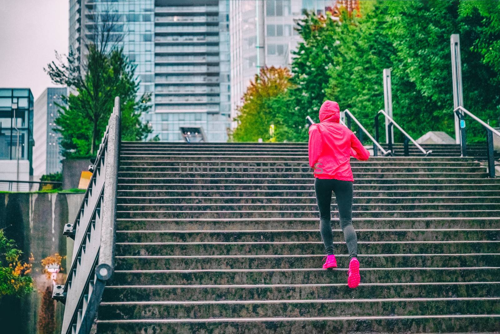 Runner running up the stairs on rain run in Vancouver city. Staircase cardio workout jogger training.