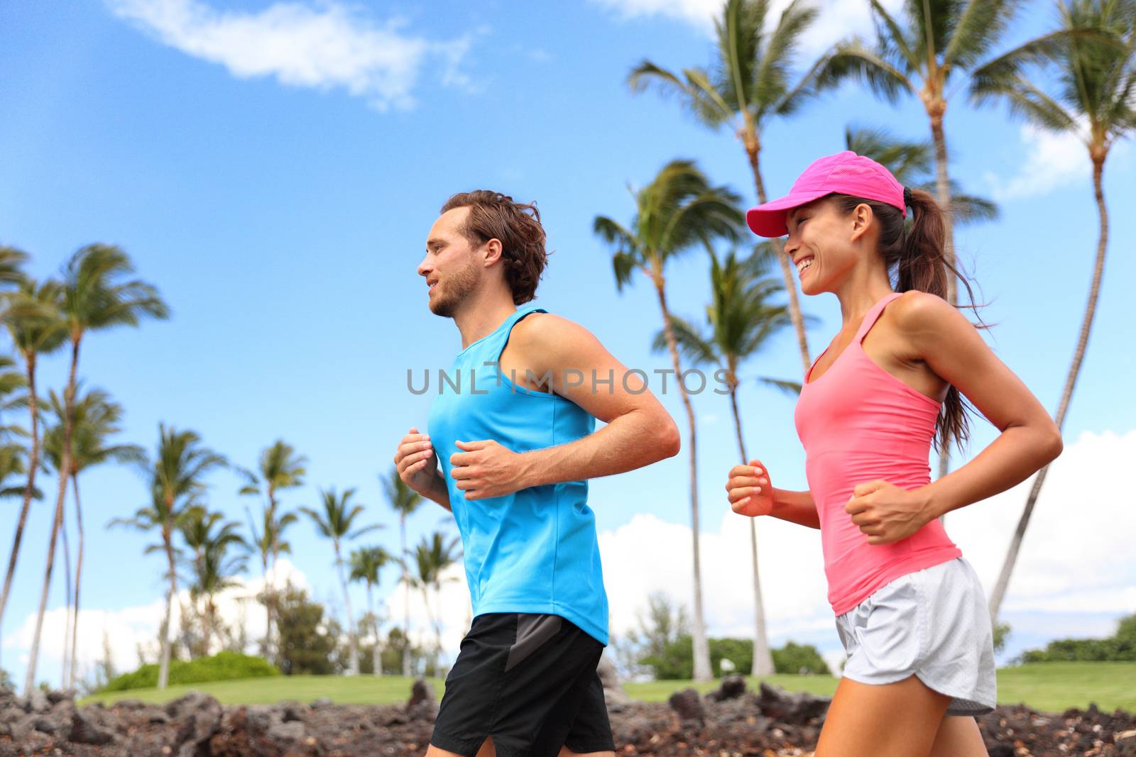 Happy couple running together training in morning summer living a healthy lifestyle. Interracial people working out in summer park by Maridav