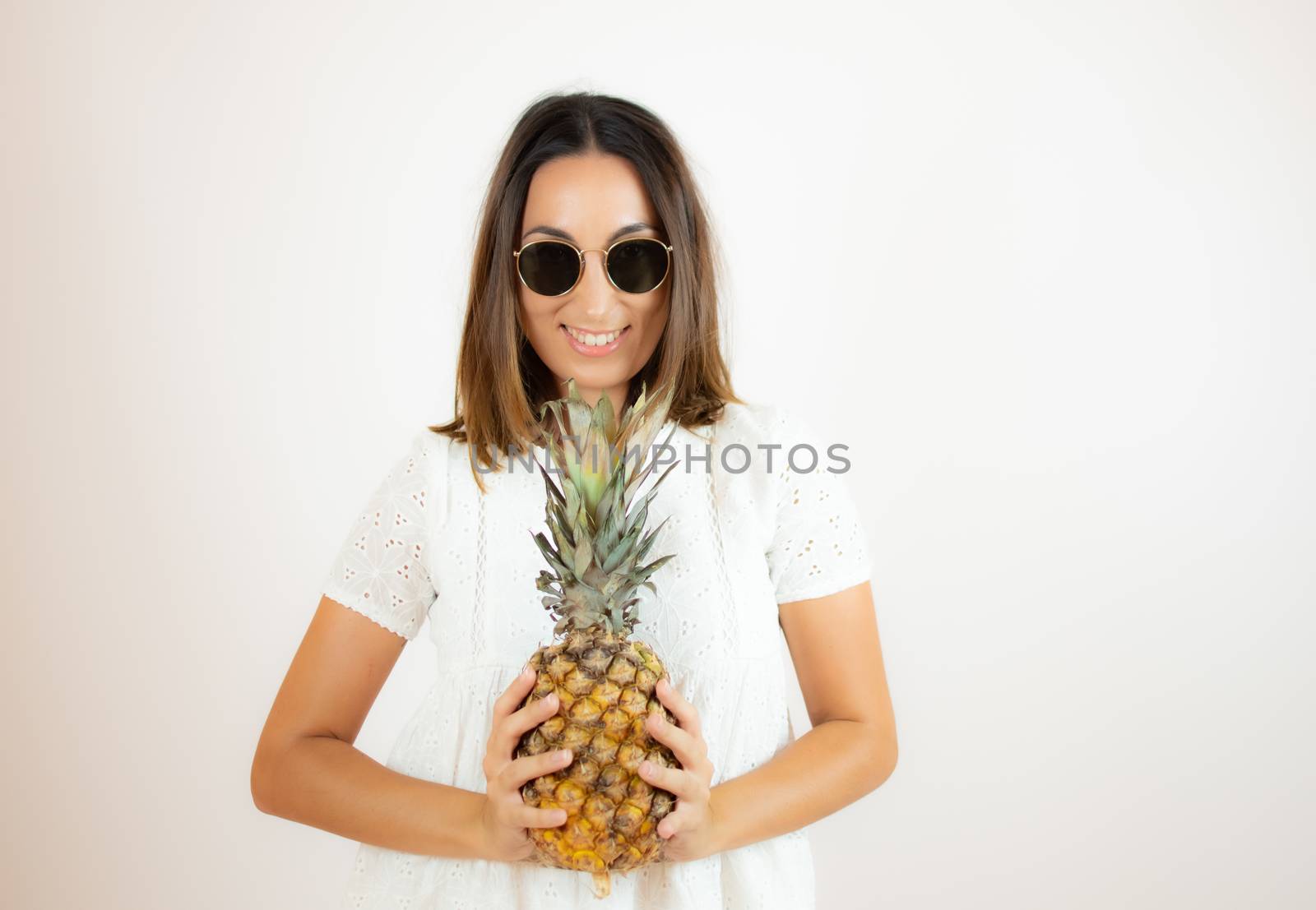 Beautiful young woman picking up a pineapple by lmstudio