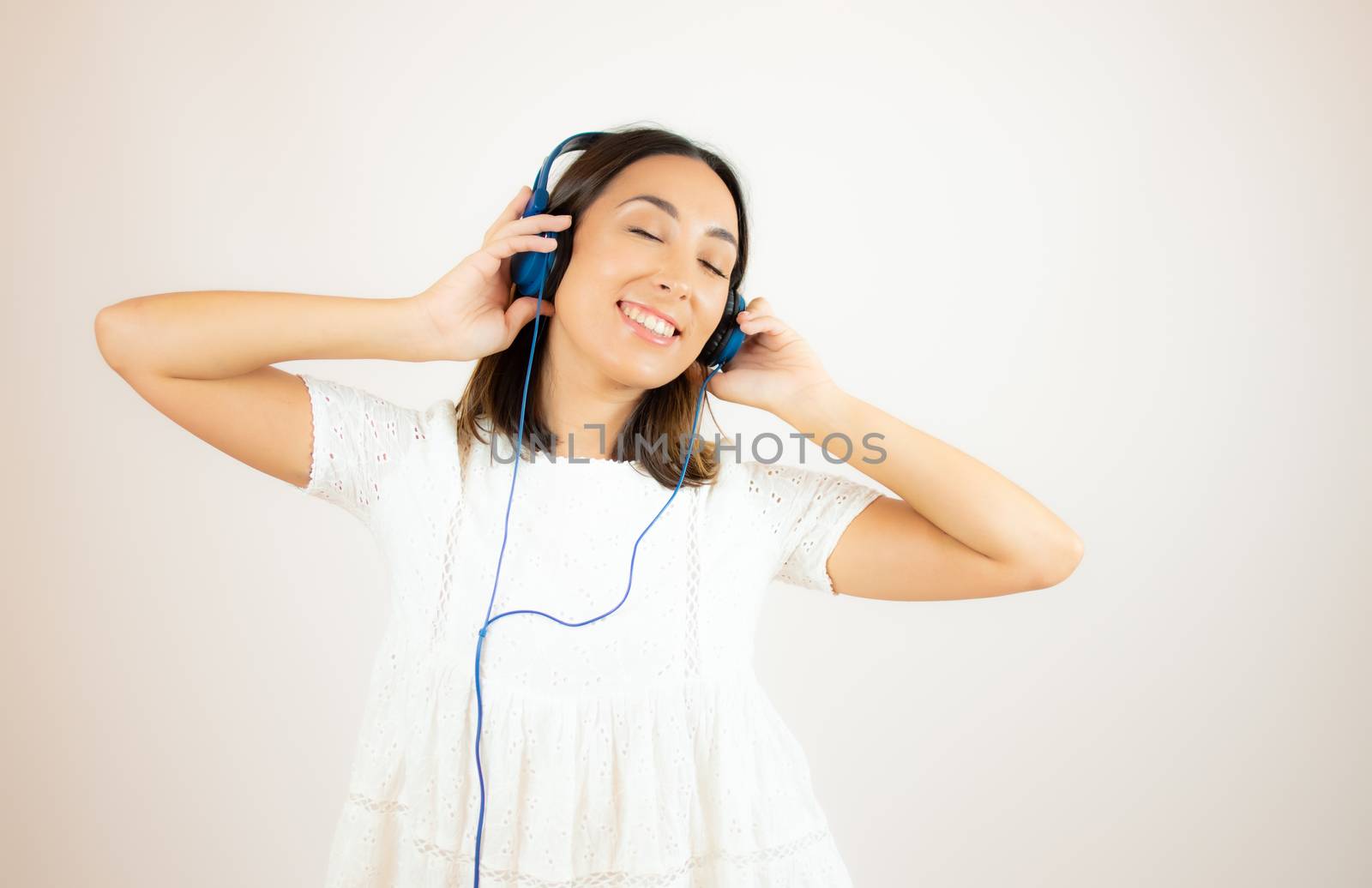 Beautiful woman in white dress with headphones by lmstudio