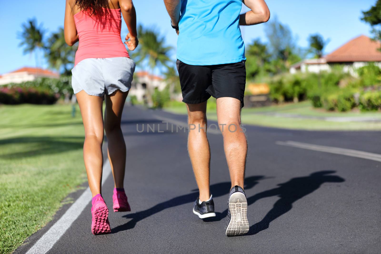 Runners running on road - closeup of legs of athletes sprinting training cardio together.