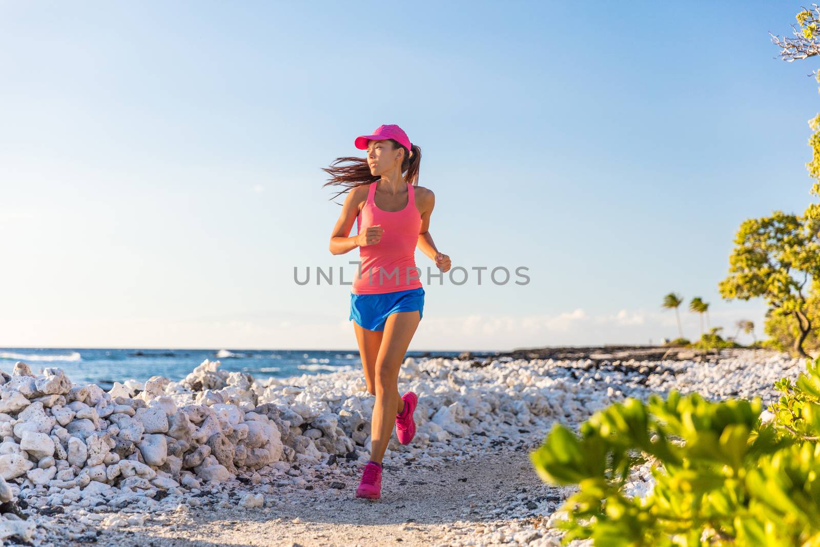 Healthy active runner girl running on beach trail path of coral rocks in Hawaii, morning training alone by Maridav