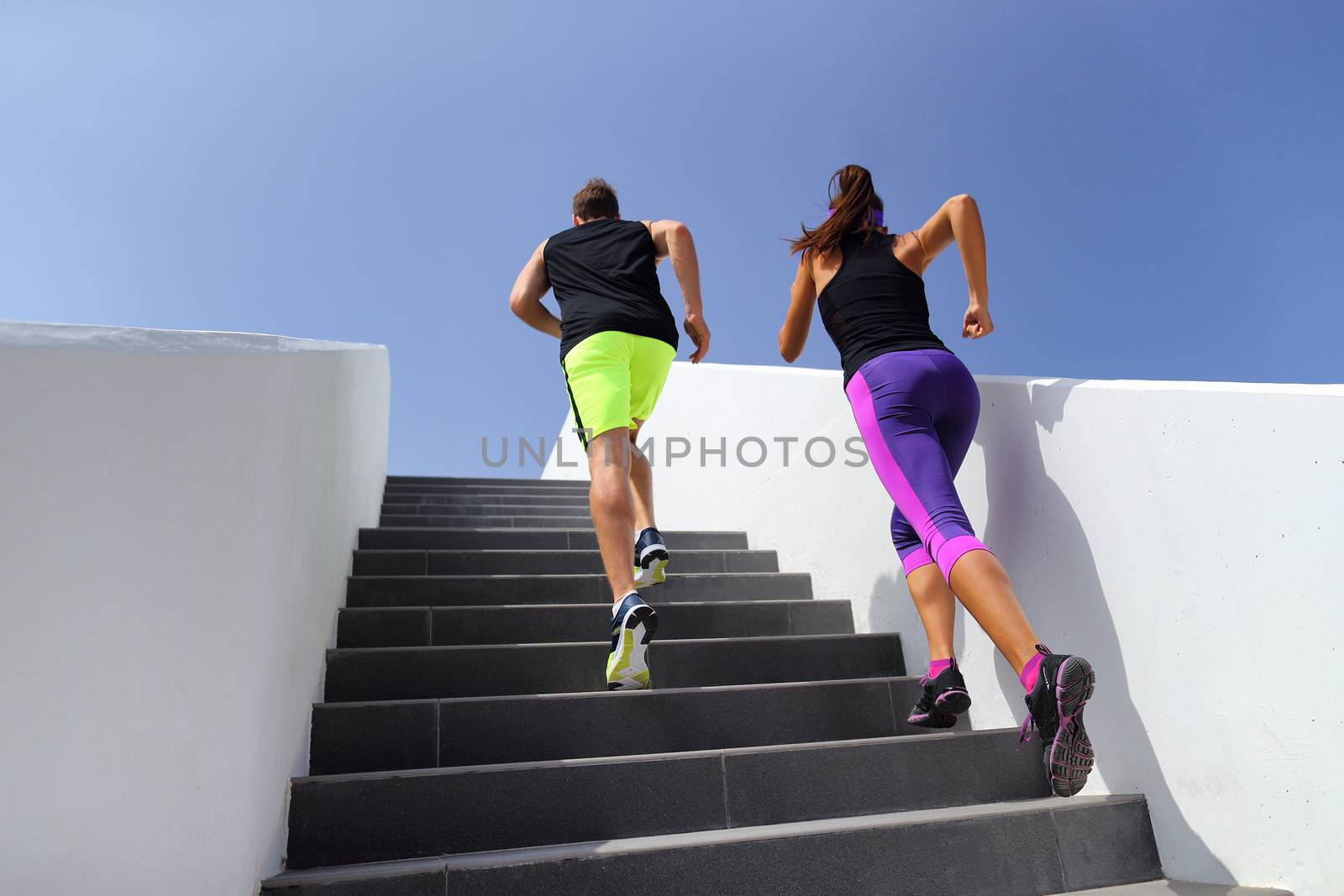 Couple running up stairs at fitness gym. Healthy active lifestyle sport people exercising cardio climbing staircase in city by Maridav