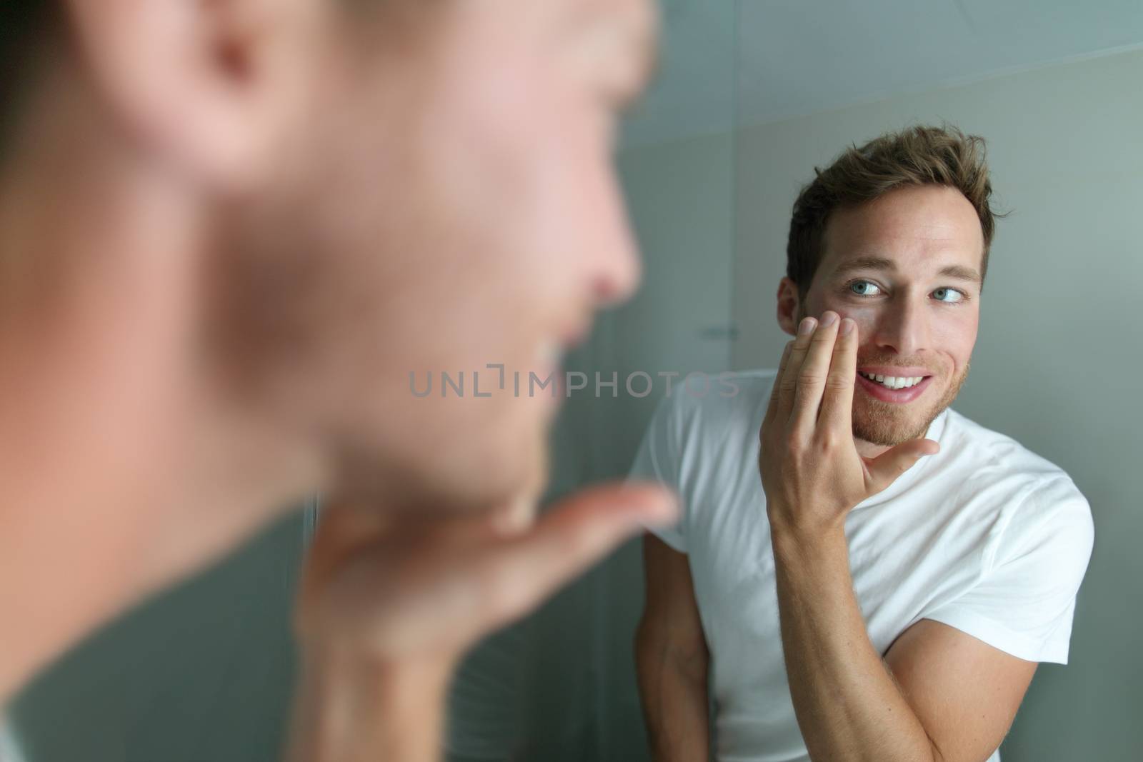 Face cream young man putting skincare beauty product on face hydrating skin. Male beauty facial treatment care at home lifestyle. Person applying moisturizer for dry skin during winter by Maridav