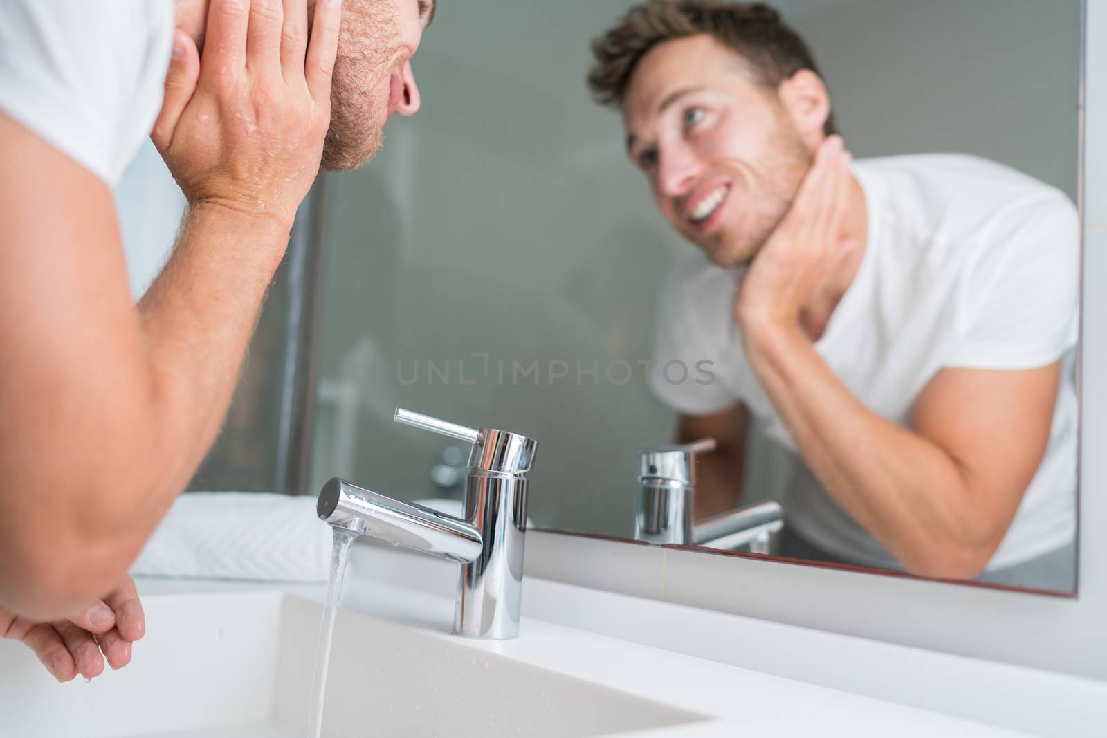 Man washing face in sink in bathroom rinsing after shaving. Home lifestyle copyspace.