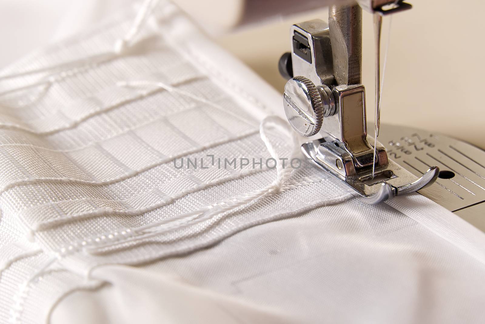 A worker works on a sewing machine. seamstress sews white curtains, close up view. by PhotoTime