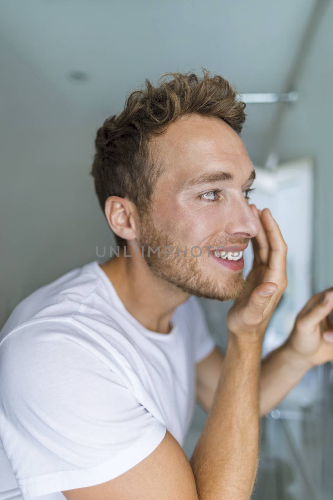 Man putting under eye cream on face taking care of his skin, Anti-aging treatment at home. Morning routine young male beauty lifestyle.