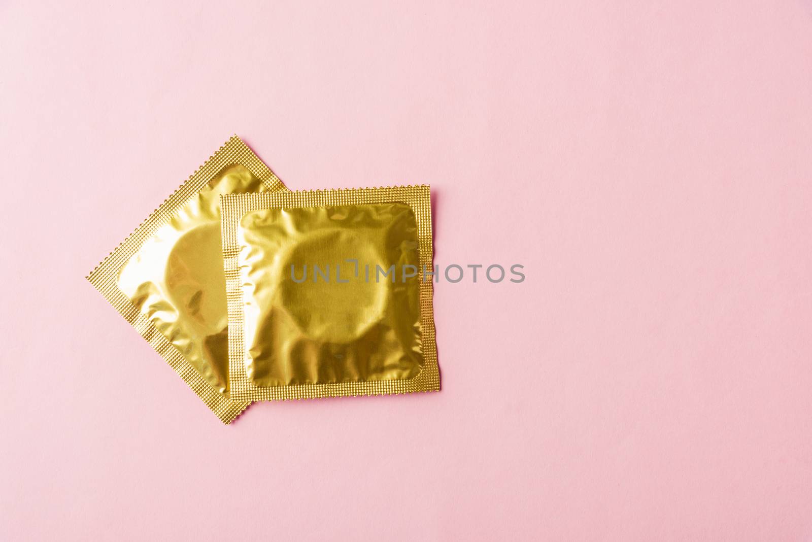 World sexual health or Aids day, Top view flat lay condom in wrapper pack, studio shot isolated on a pink background, Safe sex and reproductive health concept