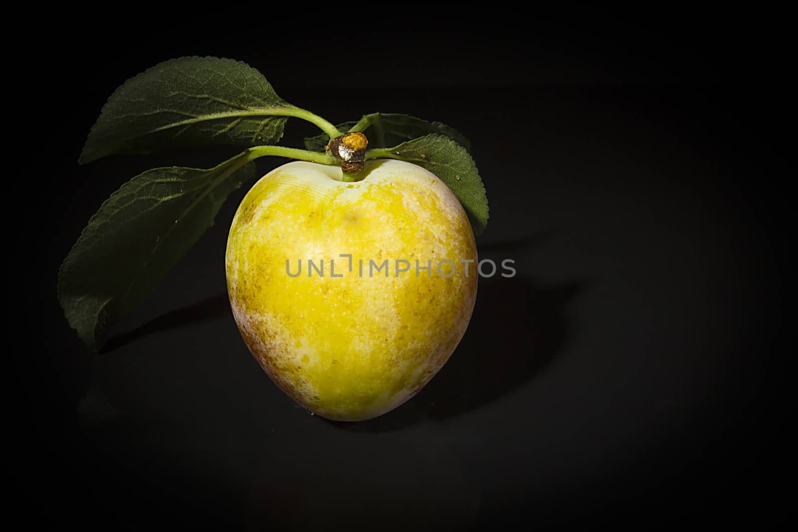 Ripe plums on a black reflective surface