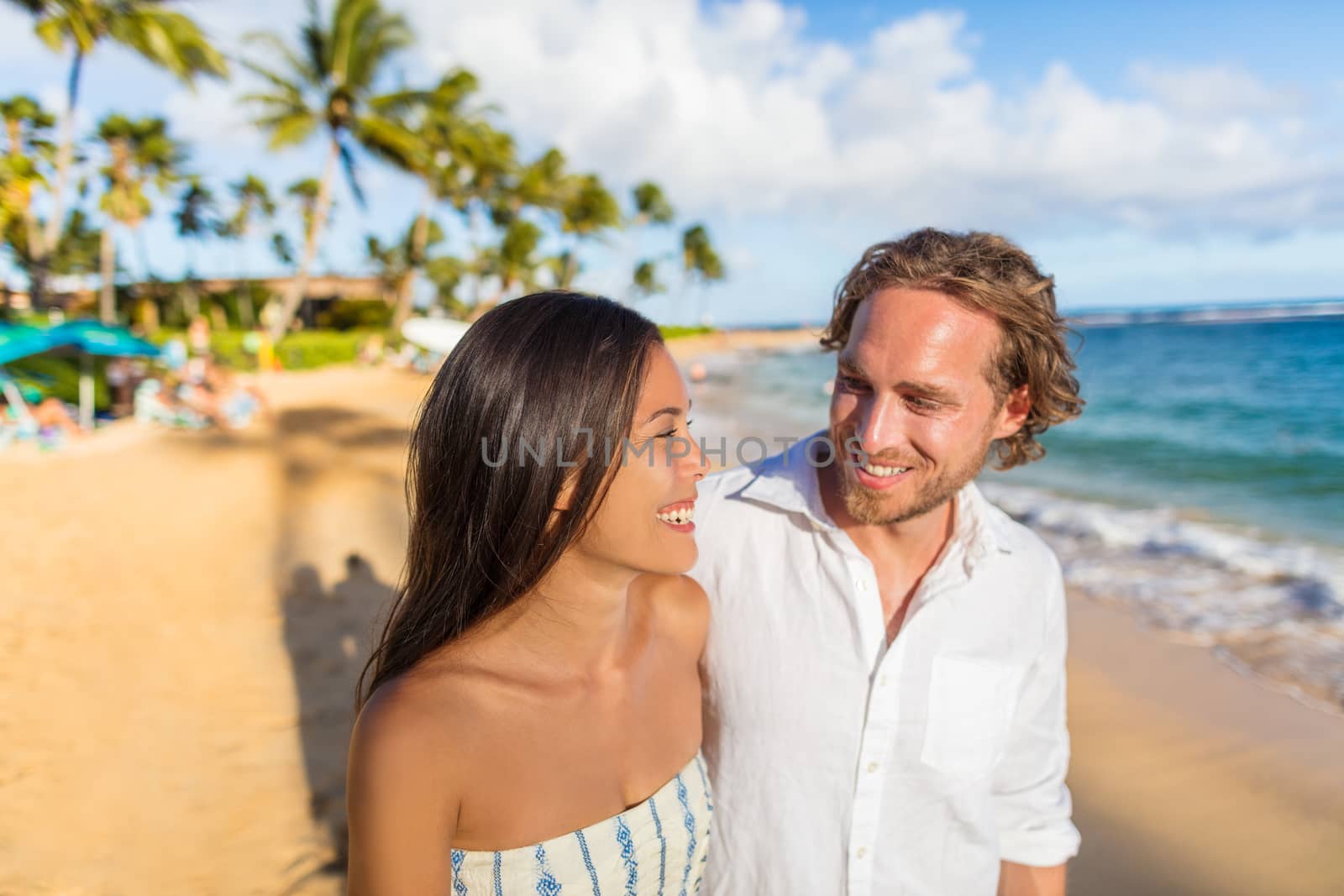 Hawaii travel beach couple laughing together happy on honeymoon vacation. People enjoying hawaiian sunset holidays.