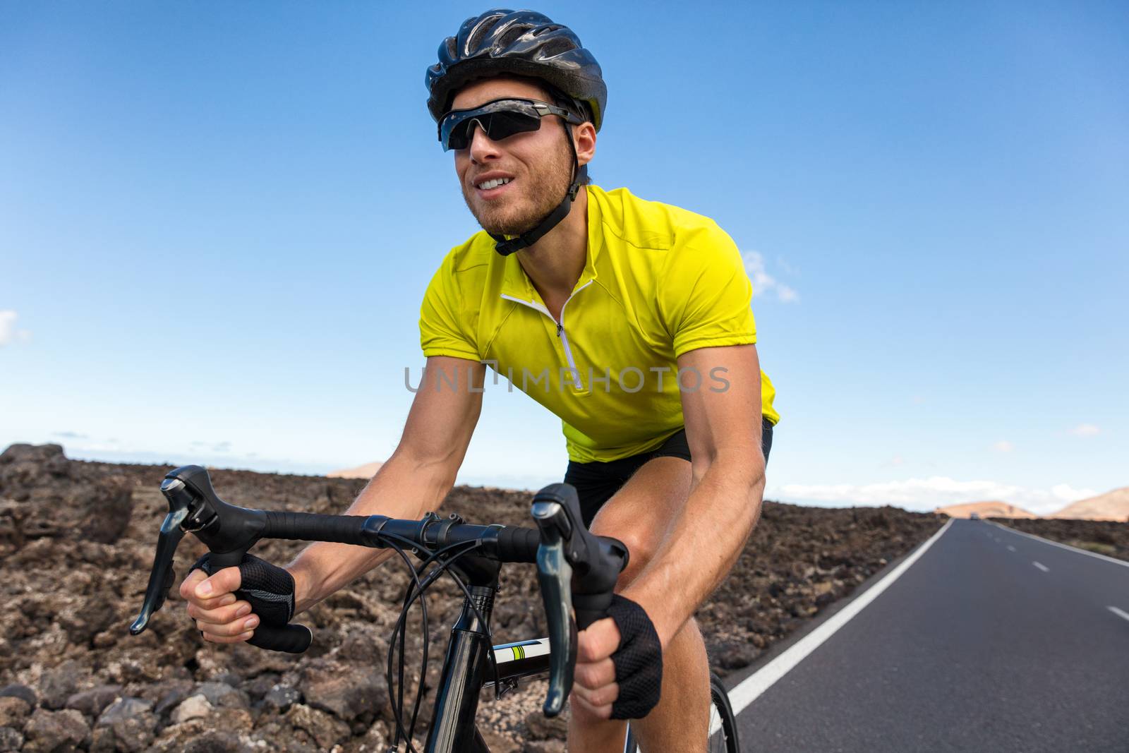 Cyclist man biking riding road bike training for triathlon. Biker on cardio workout on open road. Professional sports athlete living an active and healthy lifestyle.