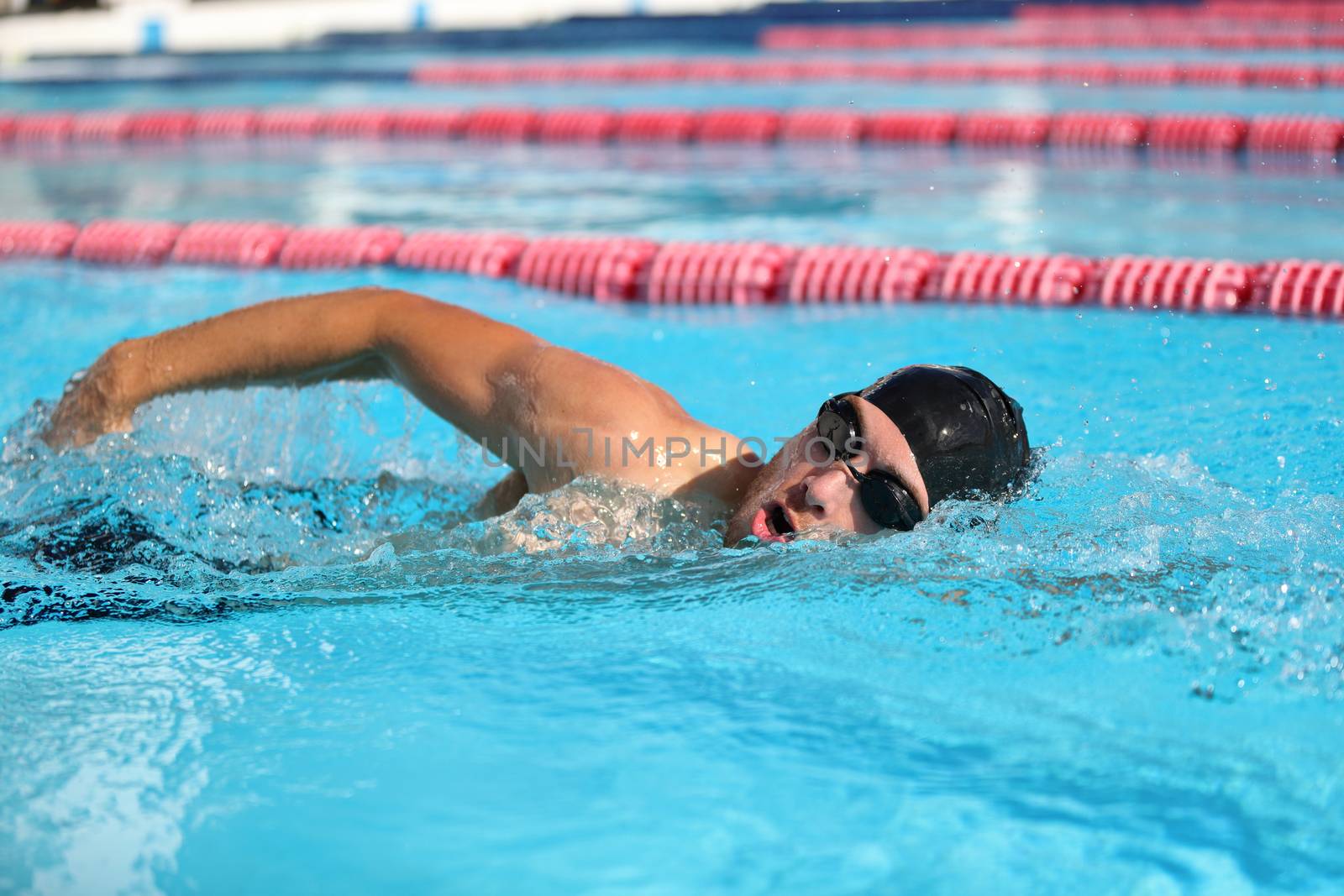 Swim competition swimmer athlete doing crawl stroke in swimming pool. Sports man male swimmer with goggles and cap breathing racing in indoor stadium. Speed exercise workout by Maridav