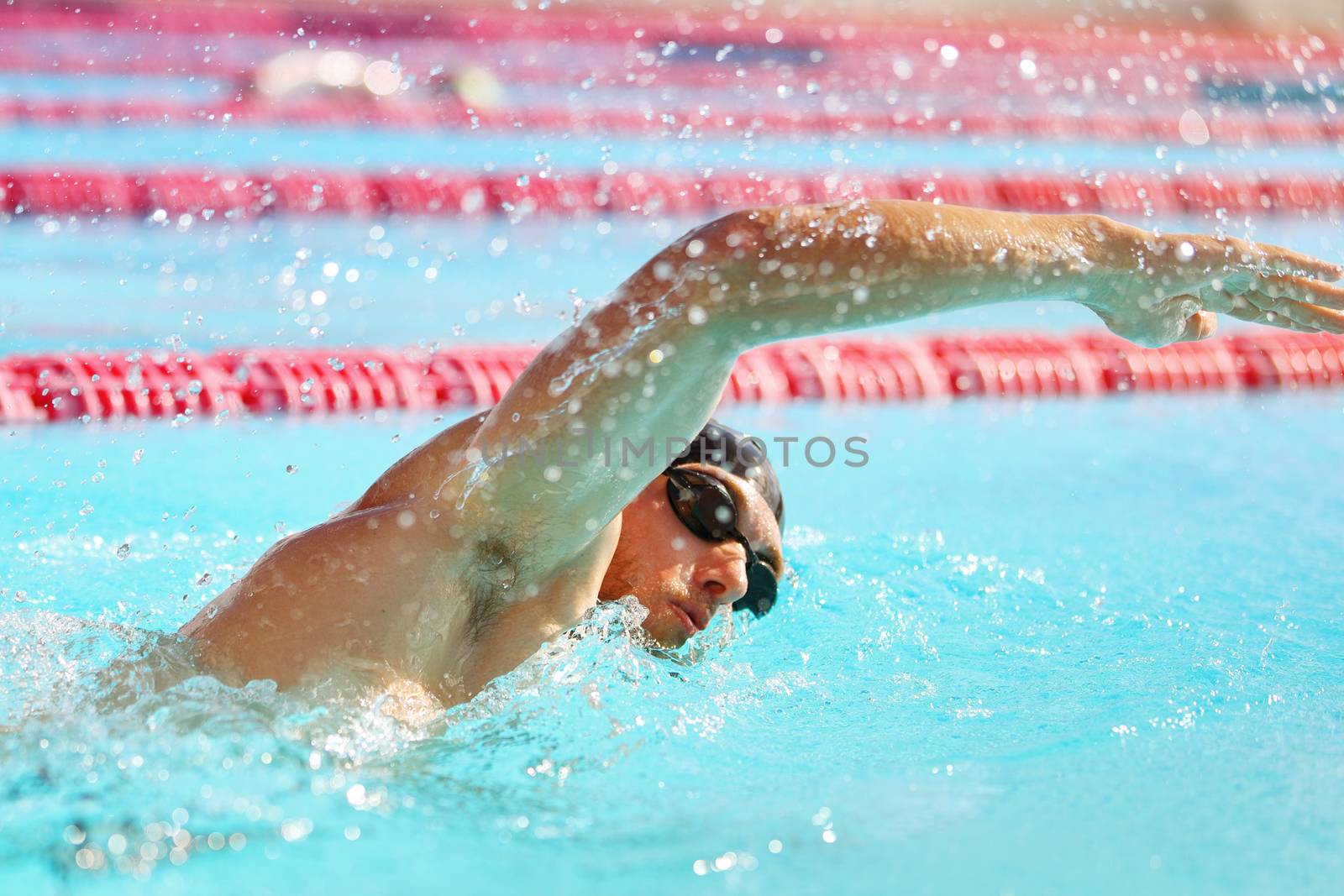 Triathlon fit athlete training in swimming pool lane at outdoor stadium. Swimmer man swimming in summer. Sports and fitness people lifestyle by Maridav