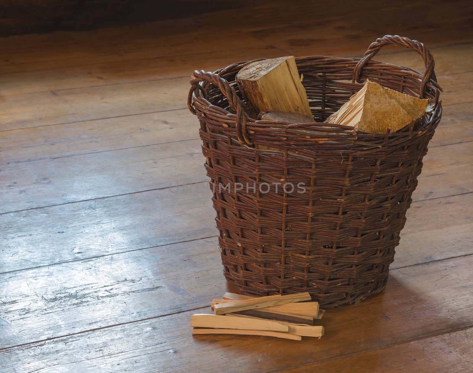 wicker basket with chopped wood and splinter pile on wooden board floor
