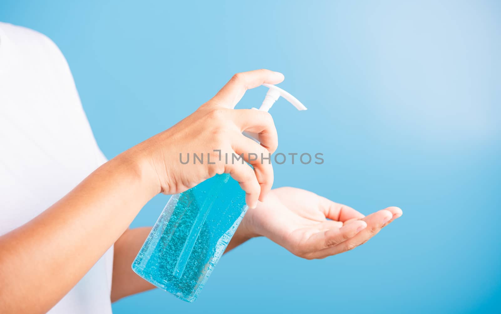 Closeup Hand Asian young woman applying pump dispenser sanitizer alcohol gel on hand wash cleaning, hygiene prevention COVID-19 or coronavirus protection concept, isolated on blue background