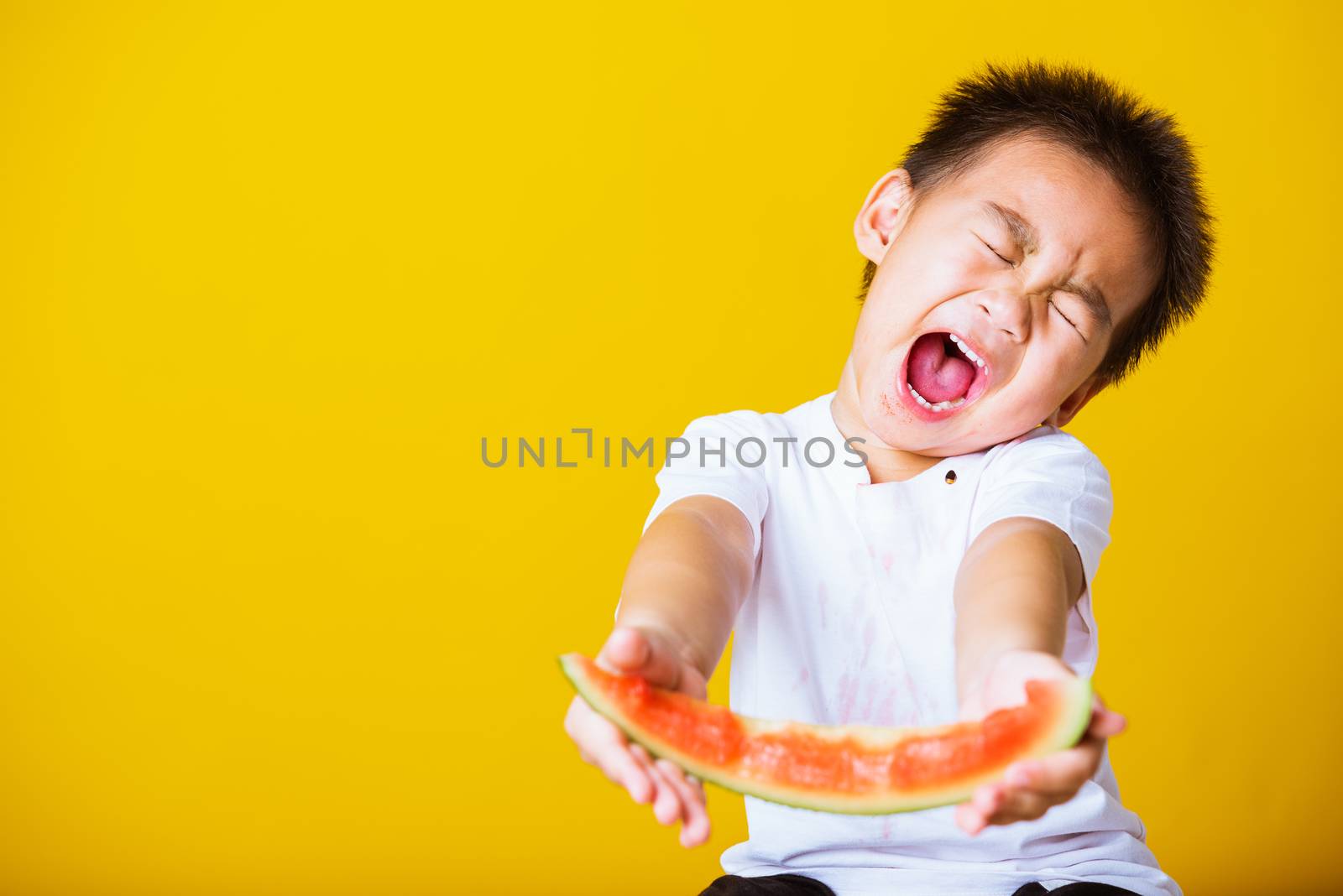 Happy portrait Asian child or kid cute little boy attractive laugh smile playing holds cut watermelon fresh for eating, studio shot isolated on yellow background, healthy food and summer concept