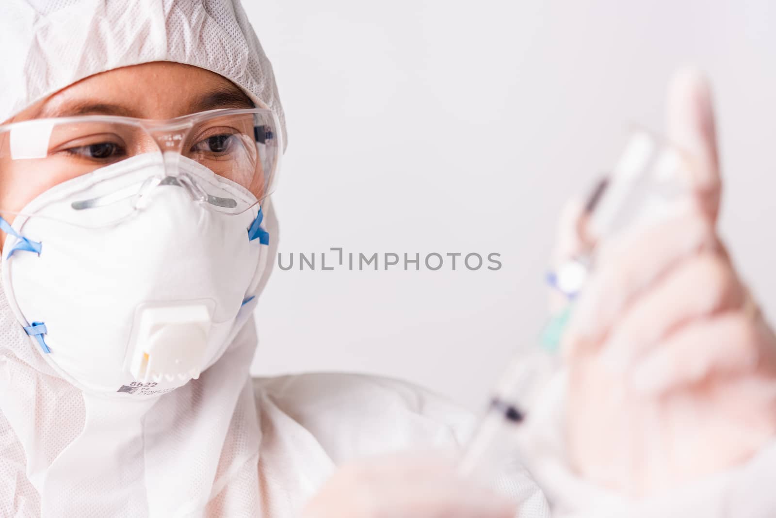 Asian female woman doctor or nurse in PPE uniform and gloves wearing face mask protective in the laboratory holding needle syringe drug and medicine vial vaccine bottle, Health medical concept