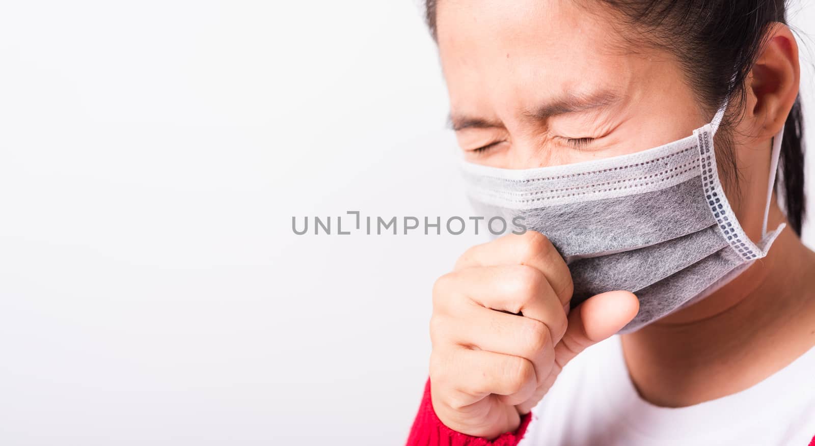 Closeup Asian adult woman wearing red shirt and face mask protective against coronavirus or COVID-19 virus or filter dust, air pollution her sneezing use hand close mouth, isolated white background