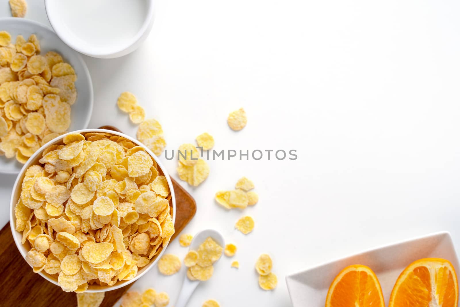 Corn flakes bowl sweeties with milk and orange on white background, top view, flat lay overhead layout, fresh and healthy breakfast design concept.