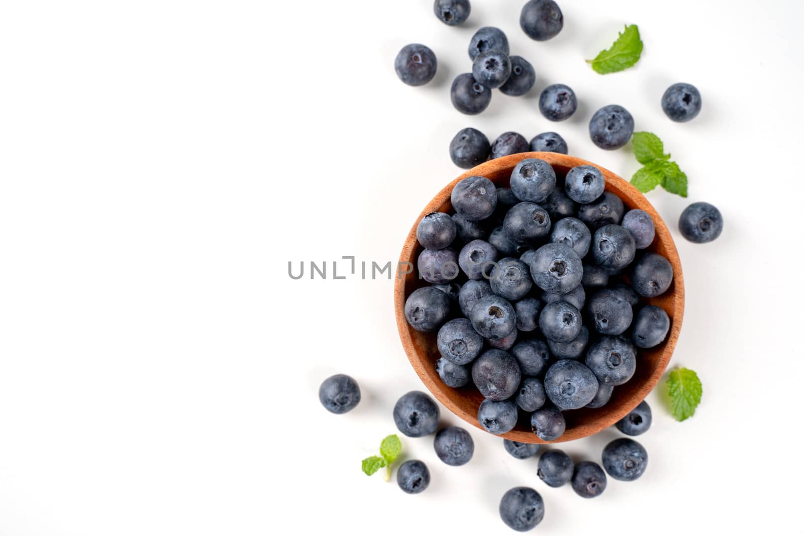 Blueberry fruit top view isolated on a white background, flat lay overhead layout with mint leaf, healthy design concept.