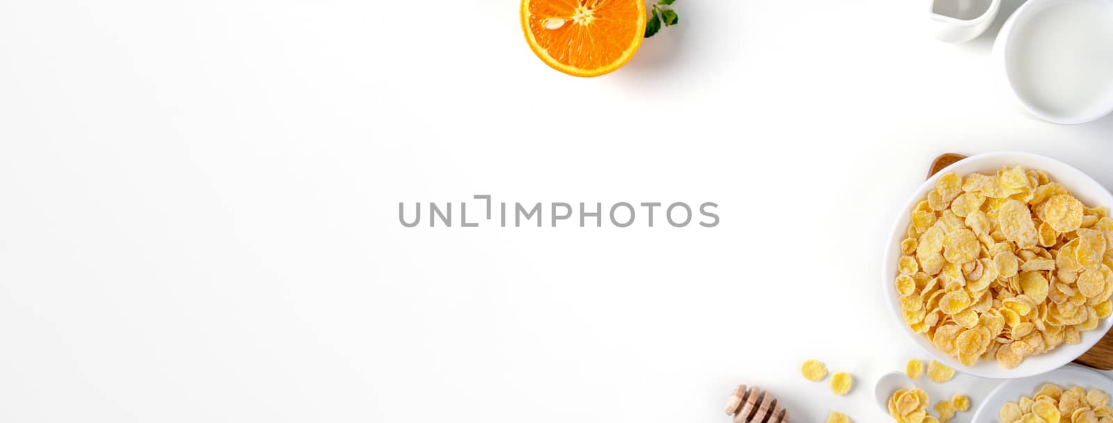 Corn flakes bowl sweeties with milk and orange on white background, top view, flat lay overhead layout, fresh and healthy breakfast design concept.