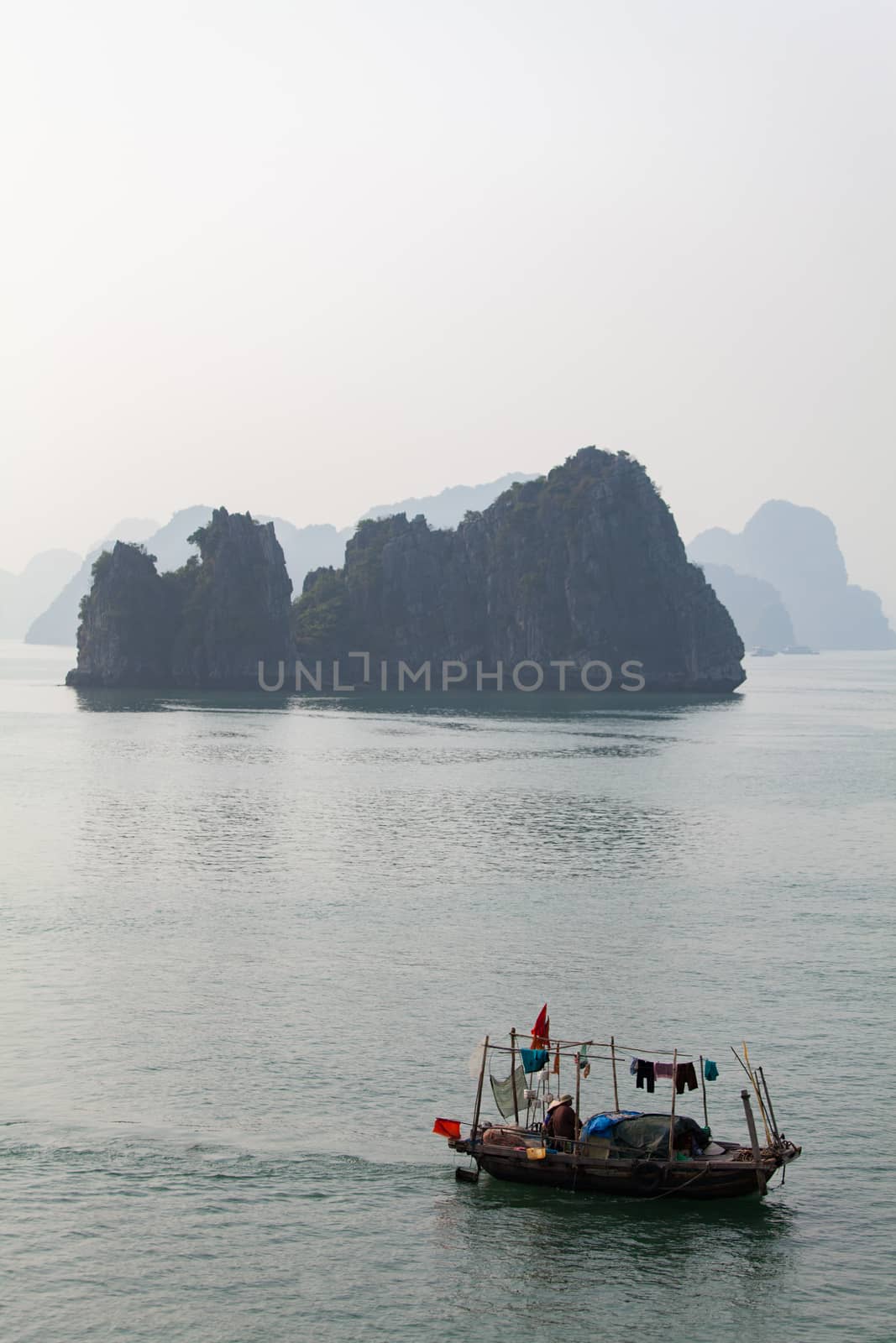 Ha Long Bay, Vietnam, is a World Heritage Site and very popular with tourists. Thousands of towering limestone islands topped by rainforests rising up out of the emerald seas. Local fishing boats. Cruise ships take tourists for day trips and overnight stays in the bay. , . High quality photo