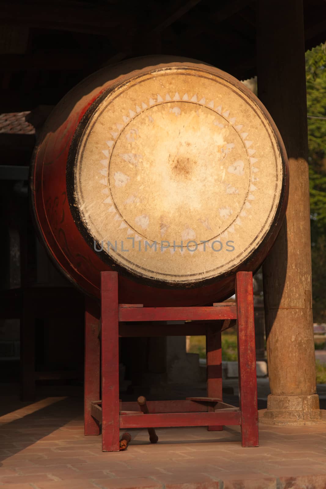 Red wooden drum on frame at entrance to Buddhist temple in Vietnam by kgboxford