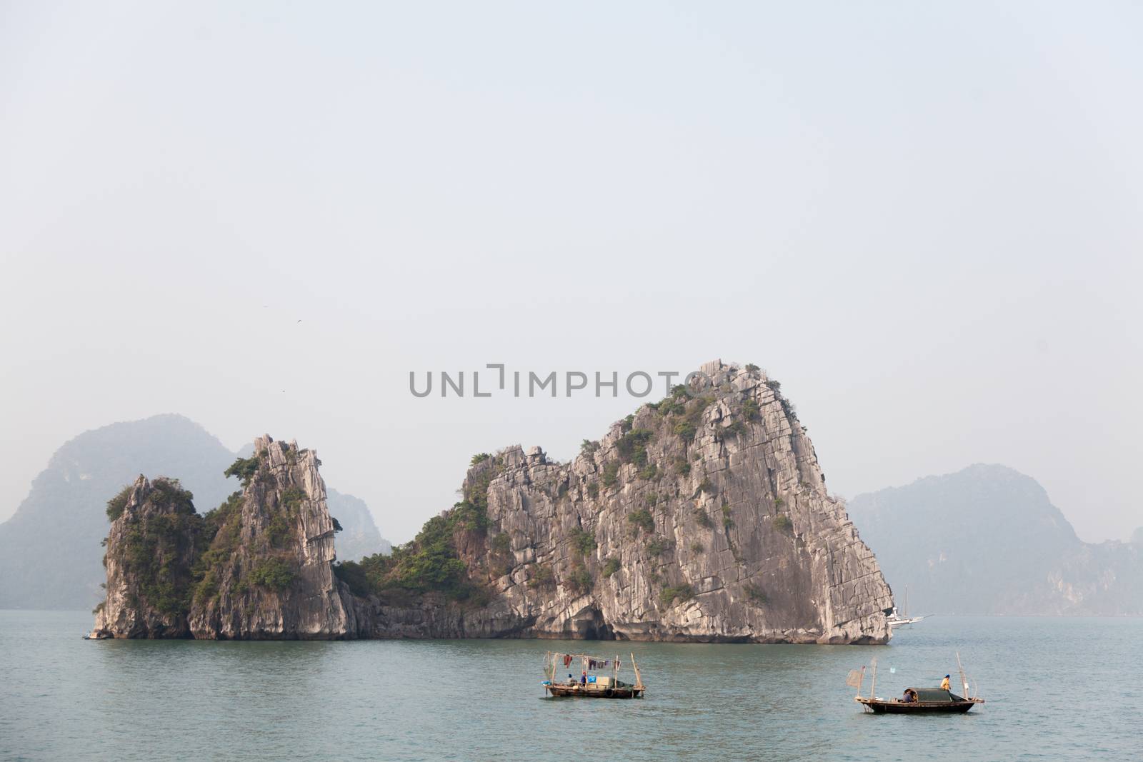 Ha Long Bay, Vietnam, is a World Heritage Site and very popular with tourists. Thousands of towering limestone islands topped by rainforests rising up out of the emerald seas. Cruise ships take tourists for day trips and overnight stays in the bay. Traditional fishing boats in the seas, . High quality photo