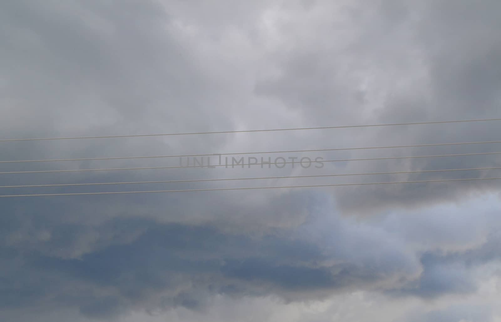 Electricity transmission power lines, high voltage lines. Storm clouds in dark danger sky