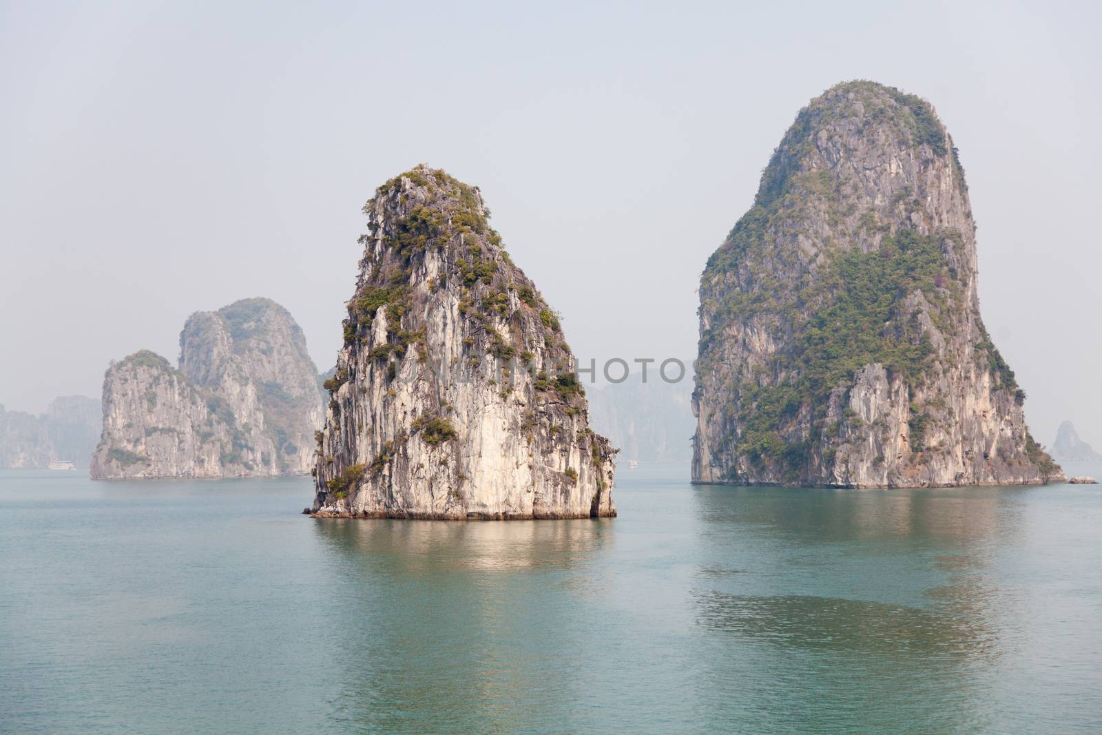 Ha Long Bay, Vietnam, is a World Heritage Site and very popular with tourists. Thousands of towering limestone islands topped by rainforests rising up out of the emerald seas. Cruise ships take tourists for day trips and overnight stays in the bay. , . High quality photo