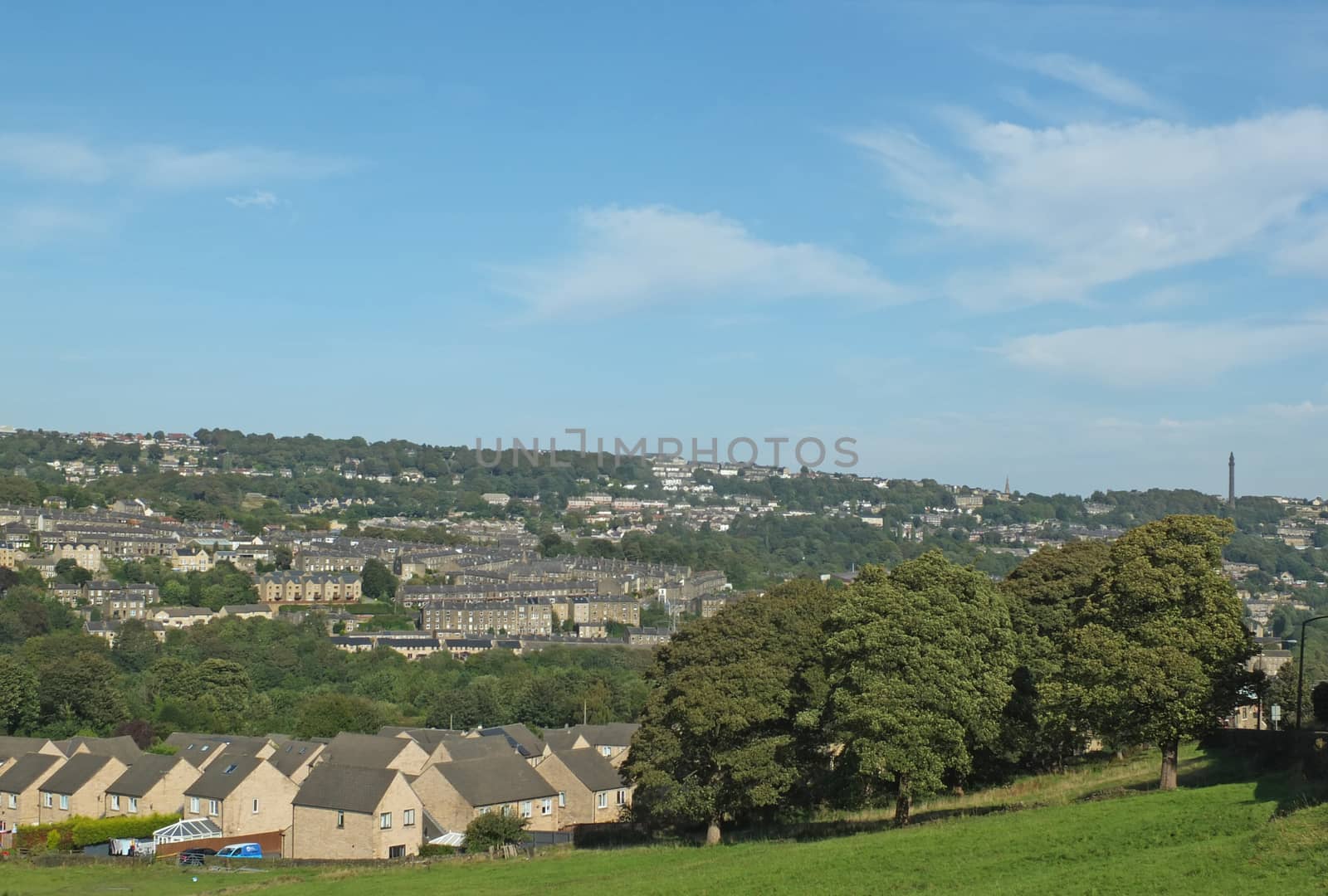 a panoramic view of halifax from above surrounded by Fields and pennine hills and a blue summer sky